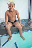 Cute little boy sitting poolside