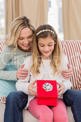 Daughter opening christmas gift with mother