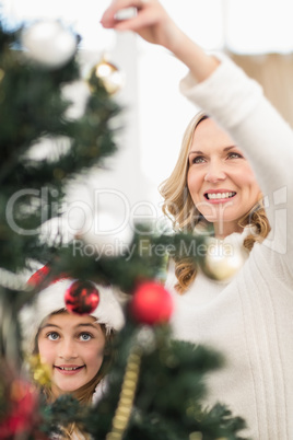 Festive mother and daughter decorating christmas tree