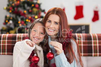Festive mother and daughter holding baubles