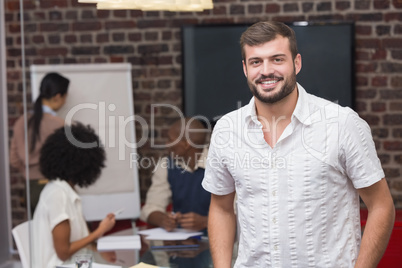 Smiling young businessman with colleagues in background