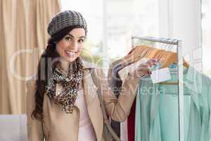 Smiling brunette holding price tag on shirt