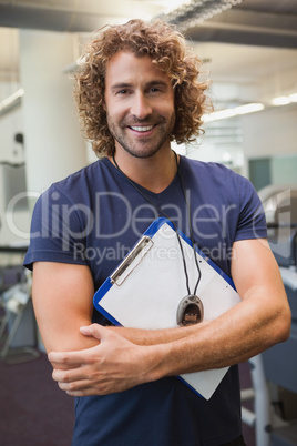 Smiling handsome trainer with clipboard in gym