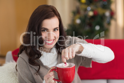 Brunette dunking marshmallow in hot chocolate at christmas