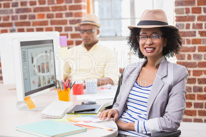 Smiling female photo editor at office desk
