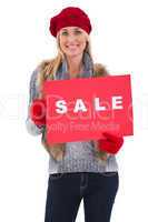 Blonde in winter clothes holding sale sign