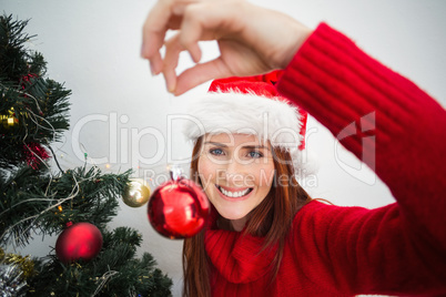 Festive redhead hanging bauble on tree