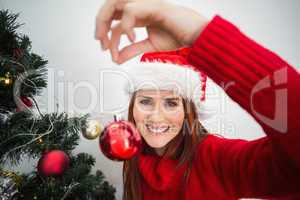 Festive redhead hanging bauble on tree