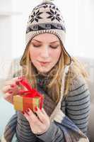 Pretty woman sitting on a couch while opening a gift box