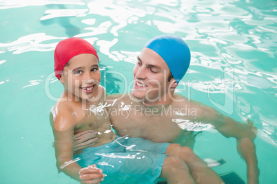 Cute little boy learning to swim with coach