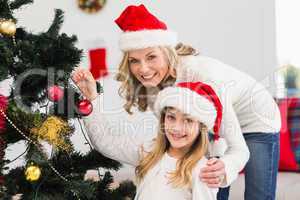 Festive mother and daughter decorating christmas tree
