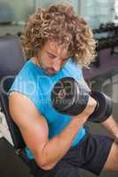 Handsome man exercising with dumbbell in gym