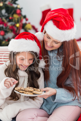 Festive mother and daughter on the couch with cookies