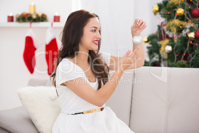 Happy brunette holding a bauble at christmas