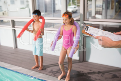 Swimming coach holding clipboard poolside