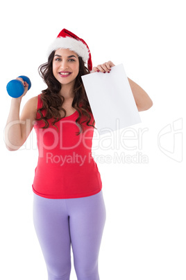 Festive fit brunette holding page and dumbbell
