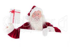 Santa shows a present while holding sign
