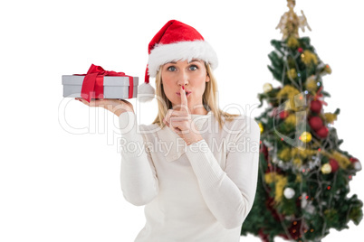 Festive blonde holding gift by the tree