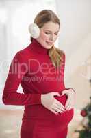 Pregnant woman making a heart with her hands on her belly