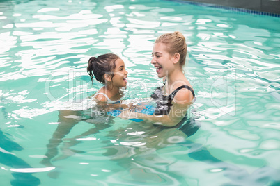 Cute little girl learning to swim with coach