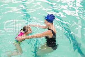 Cute little girl learning to swim with coach