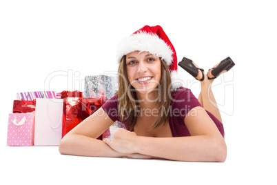 Festive brunette smiling at camera with gift bags behind her