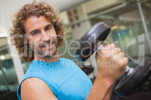 Handsome man exercising with dumbbell in gym