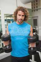 Young man exercising with dumbbells in gym