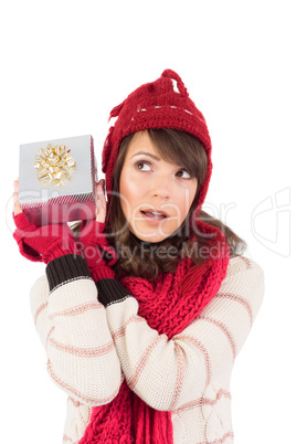 Young woman shaking her gift in order to guess what it is