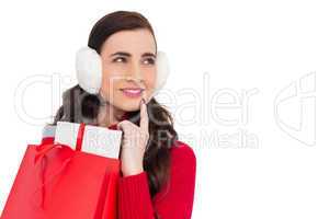 Brunette with ear muffs holding shopping bag full of gifts