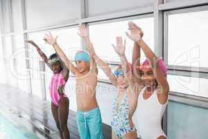 Cute little kids standing poolside with arms up