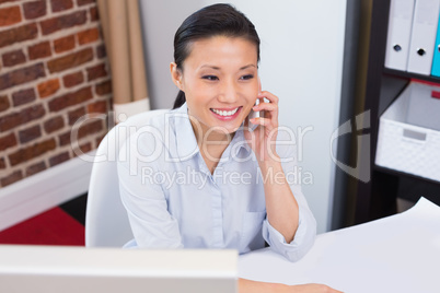 Smiling executive using mobile phone at desk Smiling executive using mobile phone at desk