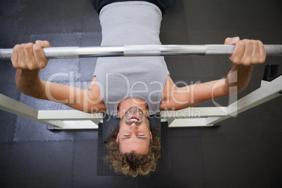 Muscular man lifting barbell in gym