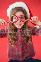 Happy little girl in santa hat holding candy canes