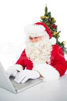 Santa using his laptop near christmas tree