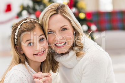 Festive mother and daughter beside christmas tree