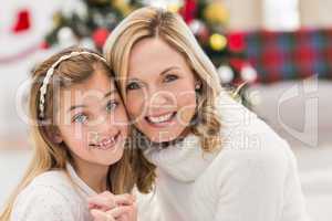 Festive mother and daughter beside christmas tree