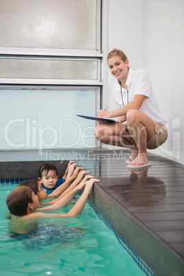 Cute kids in the swimming pool listening to coach