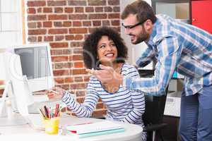 Smiling photo editors using computer in office