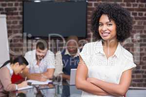 Smiling businesswoman with colleagues in background at office