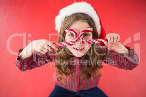 Happy little girl in santa hat holding candy canes