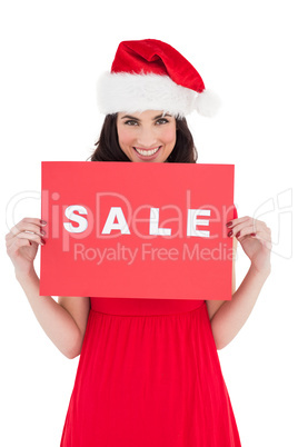 Festive brunette in red dress holding sale sign