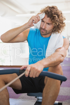 Tired man using resistance band in gym