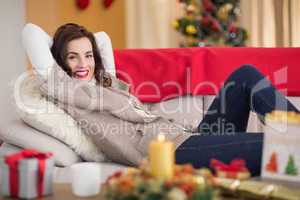 Smiling brunette relaxing on the couch at christmas