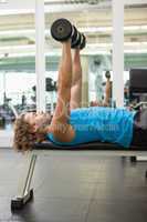 Side view of man exercising with dumbbells in gym