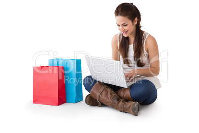 Smiling brunette sitting and using her laptop