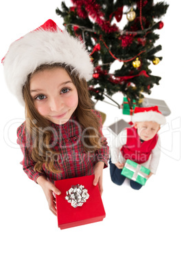 Festive little siblings smiling at camera holding gifts