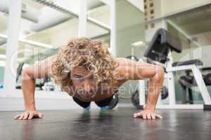 Handsome young an doing push ups in gym