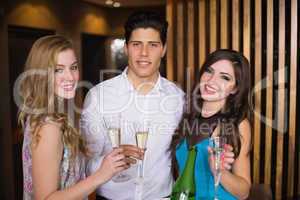 Attractive friends smiling at camera holding champagne