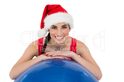 Festive fit brunette leaning on exercise ball